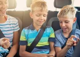 A group of kids laughing and playing rock, paper, scissors in a car during a road trip
