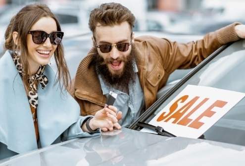 Excited couple buying a car during a sale without noticing red flags.