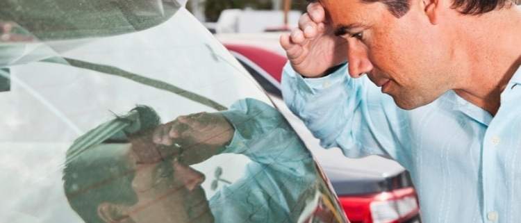 A person examining a demo car at a dealership, pondering the advantages and disadvantages.