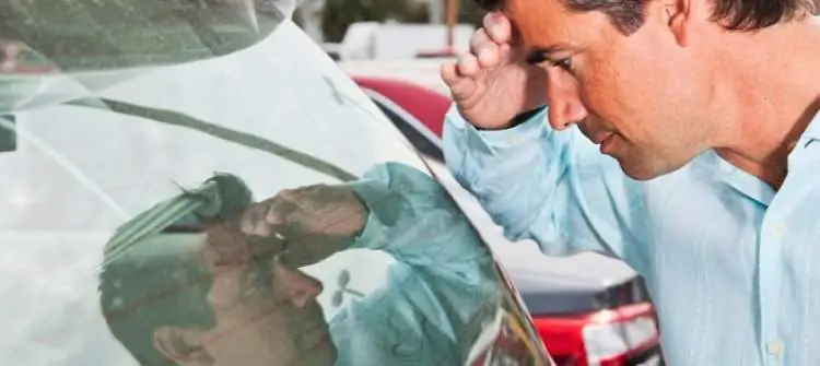 Buying a Demo Car: Pros and Cons Explained A person examining a demo car at a dealership, pondering the advantages and disadvantages.