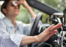 Woman sweating and struggling in a car without air conditioning on a hot summer day.