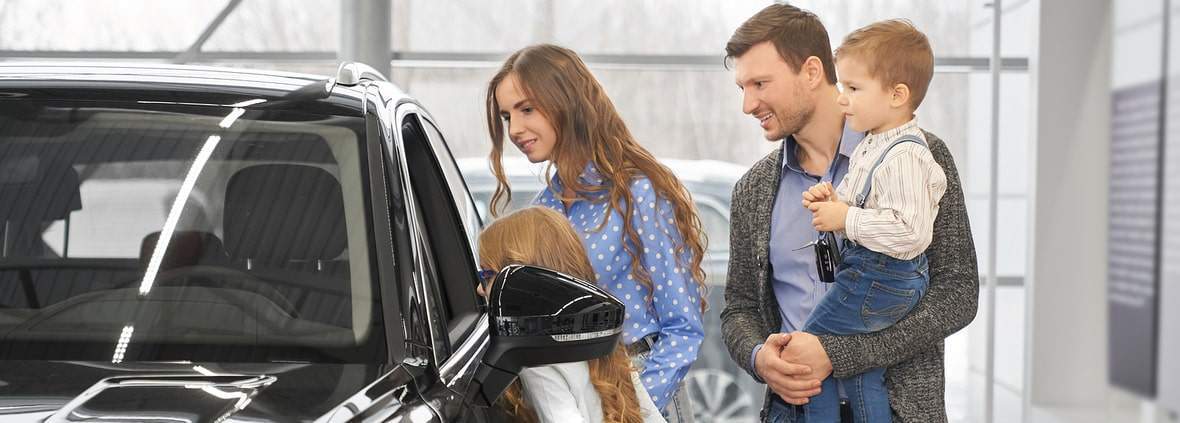 Happy family buying a new car at a dealership in 2024.