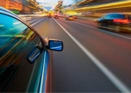 Fast drivers speeding on city road at night, illustrating risky driving behavior.