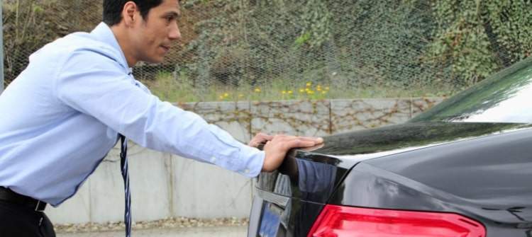 Pros and Cons of Extended Auto Warranties: Is the Investment Worth It? Business man pushing his car off the rode that broke down while driving to work.