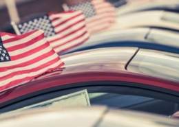 Row of cars with American flags on Memorial Day weekend car sale.