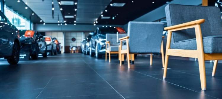 Inside a New Car Dealership Showroom – Buying Myths Uncovered. Modern car dealership showroom with new vehicles and empty customer lounge chairs.