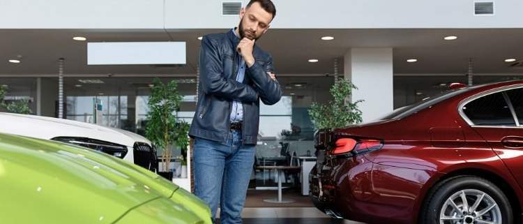 Man in a dealership thinking about buying a new car.