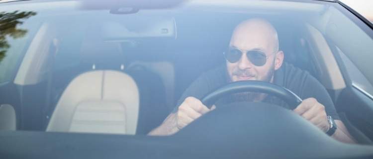Bald man driving aggressively ignoring unwritten road rules.
