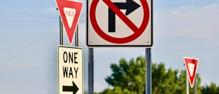 A driver confused by bizarre road signs representing weird traffic laws around the world.